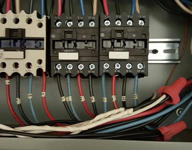 Close-up of an electrical panel showing multiple circuit breakers with connected wires labeled with numbers and color-coded.